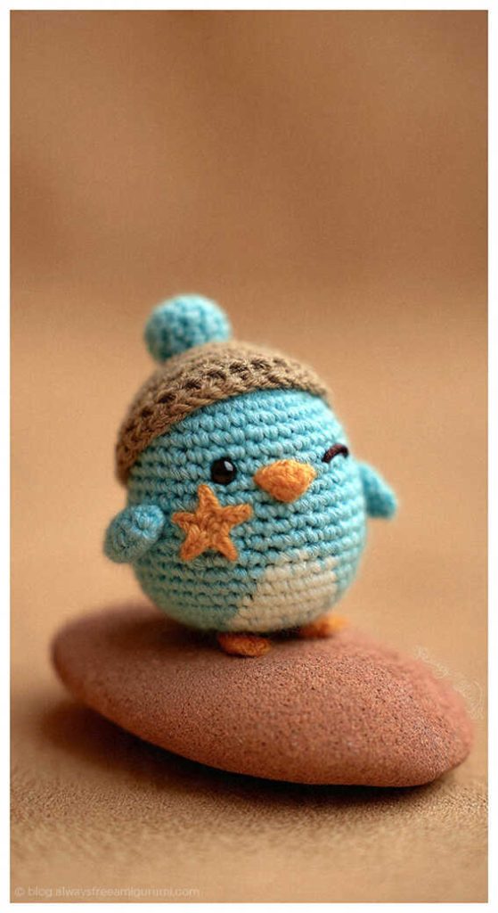 Small teal winter bird amigurumi with hat on stone, cozy handmade crochet decor idea