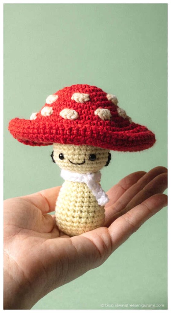 Tiny red mushroom amigurumi doll in hand, whimsical handmade nursery decor idea