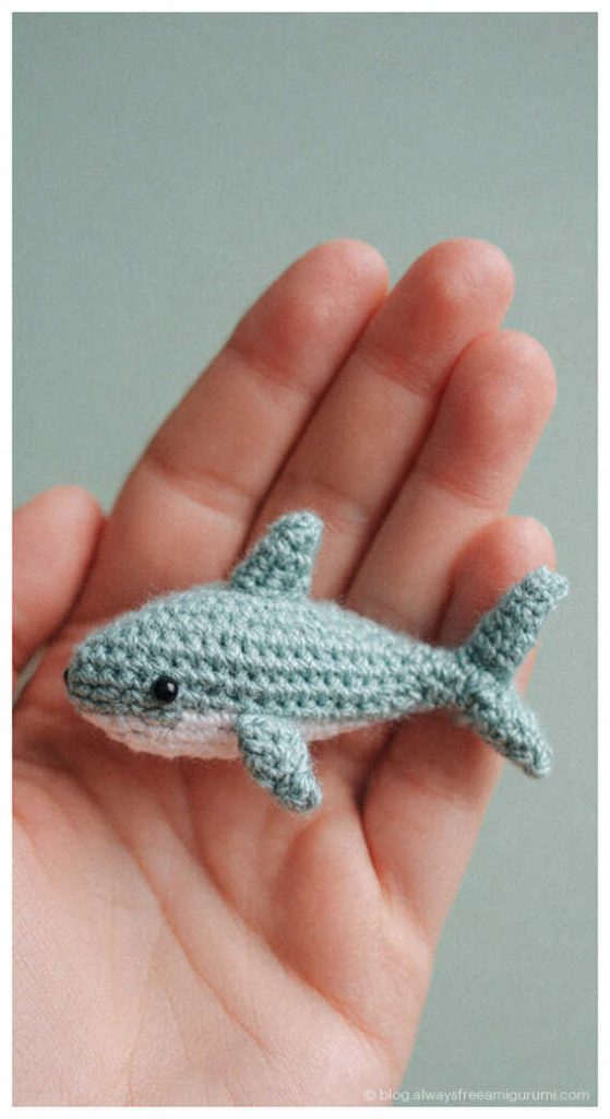 tiny crochet shark amigurumi in a hand cute small ocean animal toy handmade shark crochet close up