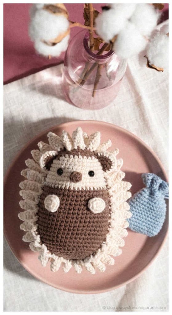 Flat hedgehog amigurumi doll on plate with tiny blue fish, creative handmade crochet decor idea