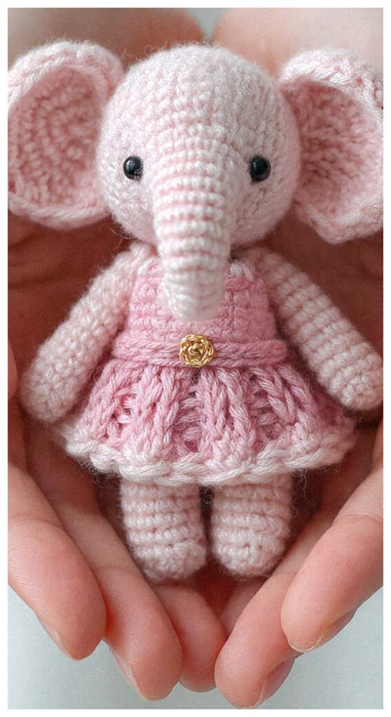 pink crochet elephant amigurumi doll in hands cute handmade elephant toy with dress