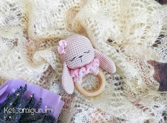 crochet bunny baby rattle flat lay free crochet pattern handmade bunny toy with wooden ring soft texture background