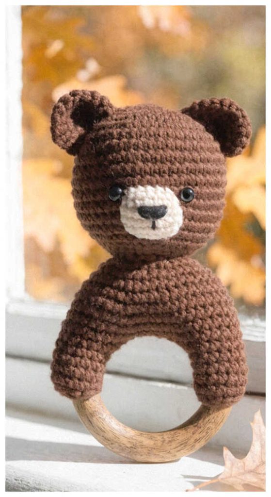 crochet bear baby rattle with wooden ring handmade baby toy by window autumn background