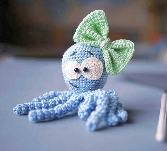 Blue octopus amigurumi with a mint bow crochet free pattern sitting on a soft pastel background