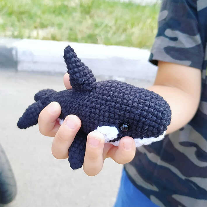 Free orca amigurumi crochet pattern featuring a handmade whale plush held outdoors